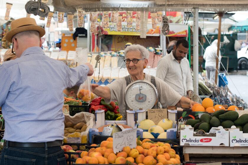 Rome, Italy- Elderly woman cashier selling a man fresh produce in Campo de' Fiori, the largest and oldest outdoor market in Rome. It is located south of Piazza Navona. (Photo by: VW Pics/Universal Images Group via Getty Images)