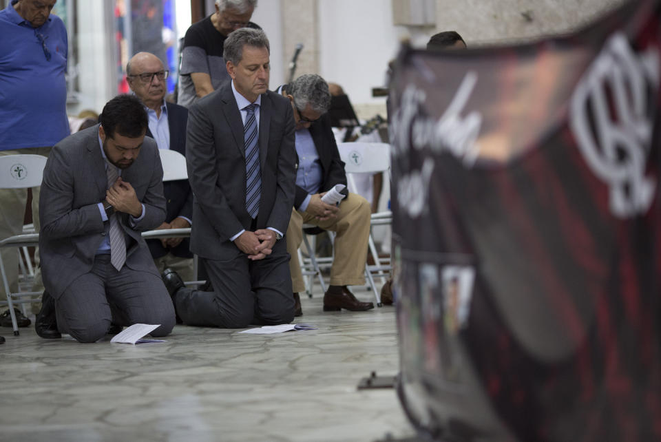 Flamengo soccer club president Rodolfo Landim, right, attends a mass in honor of the 10 teenage soccer players who were killed by a fire at the Flamengo training center last Friday, in Rio de Janeiro, Brazil, Friday, Feb. 15, 2019. The victims were between 14 and 16 years old. Police are still investigating what caused the fire. (AP Photo/Silvia Izquierdo)