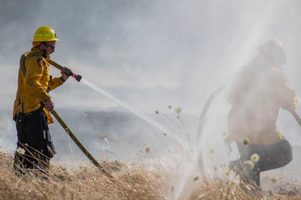 Firefighters rush to mop up the fire that broke out on Greenhill Road and Bodenhammer Road West of Eugene on Monday, July 15, 2024.