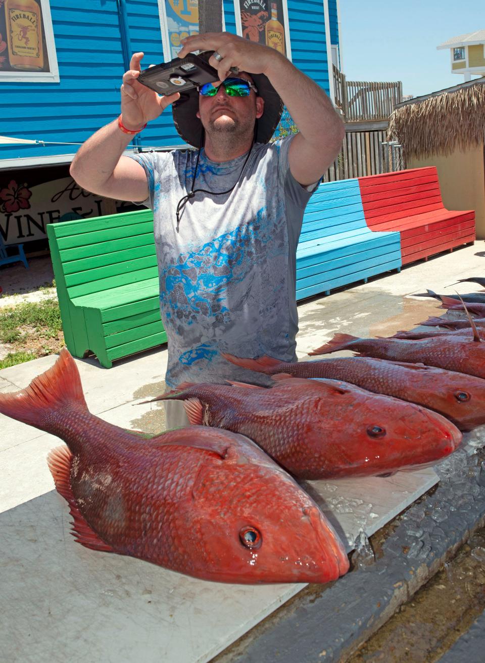 Arkansas tourist Christopher Price takes photos of his red snapper catch after a successful day of fishing on Thursday, June 16, 2022.