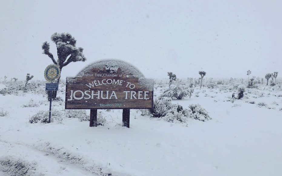 This photo provided by the San Bernardino County Sheriff's Department shows a snow covered entrance sign to Joshua Tree National Park on Thursday, Feb. 21, 2019. Forecasters say a cold weather system could bring snow to extremely low elevations of Southern California and the San Joaquin Valley. (Sgt. Daniel Hanke/County Sheriff's Department via AP)