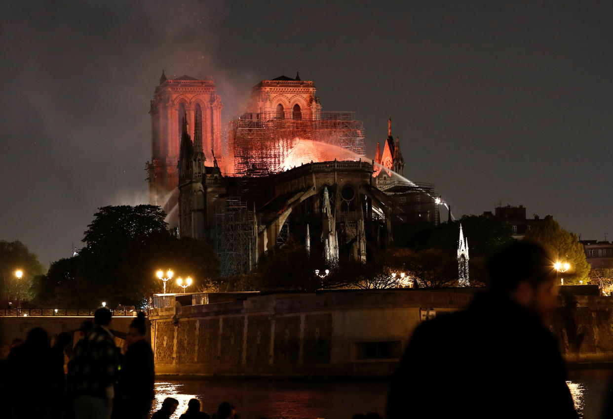 Firefighters douse flames from the burning Notre Dame Cathedral as people look on in Paris, France April 15, 2019. REUTERS/Benoit Tessier