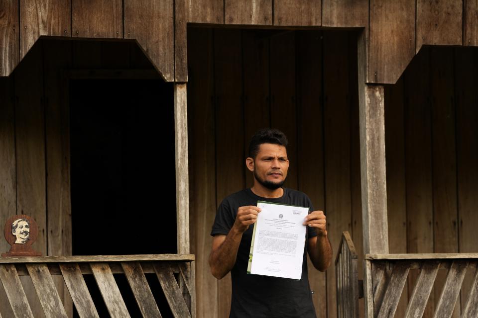 Rubber-tapper Jurivan Bezerra Rios shows a document denouncing the illegal sale of land in the Chico Mendes Extractive Reserve, in Xapuri, Acre state, Brazil, Wednesday, Dec. 7, 2022. Land-robbers from the neighboring state of Rondonia illegally bought land parcels, even on public land. (AP Photo/Eraldo Peres)
