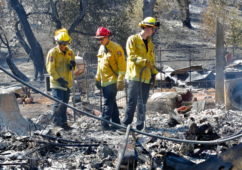 Firefighters on Friday, July 15, 2022, extinguish the still-smoldering ashes of the Peter Pan Gulch Road home of J.D. Krieger and Heather Barber that was destroyed in the Peter Fire the day before.