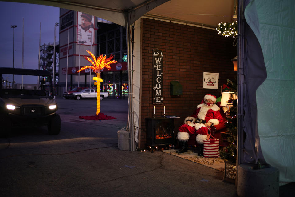 Bill Sandeen, dressed as Santa Claus, waits for cars at a drive-thru Santa selfie station at Glittering Lights, a drive-thru holiday lights display in Las Vegas, on Dec. 11, 2020. In this socially distant holiday season, Santa Claus is still coming to towns (and shopping malls) across America but with a few 2020 rules in effect. (AP Photo/John Locher)