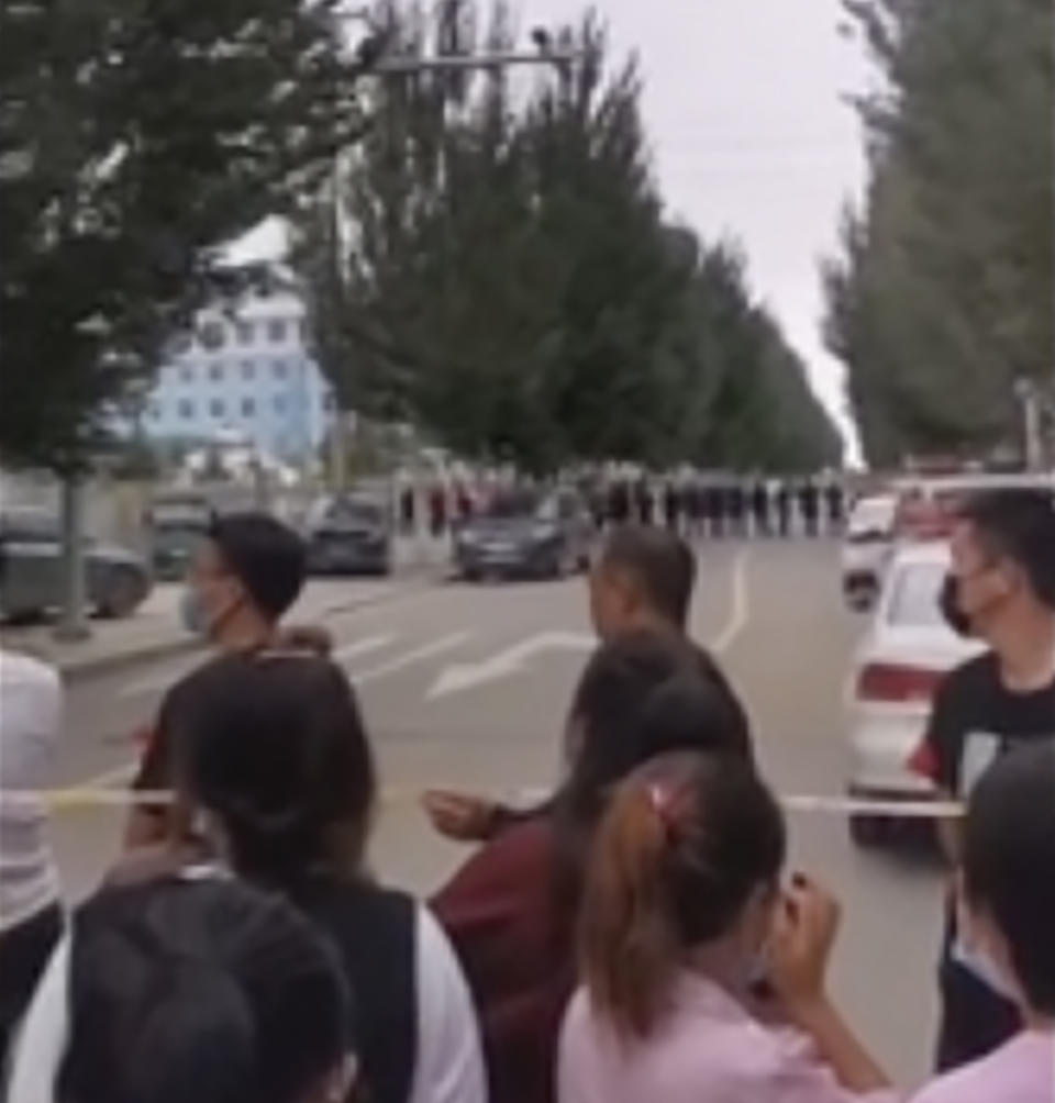 In this image made from video taken in August 2020, parents gather behind a police line outside a school in Tongliao in Northwestern China's Inner Mongolia region. Ethnic Mongolians, including students and parents, in China’s Inner Mongolia region are demonstrating their anger in rare public protests against a new bilingual education policy that they say is endangering the Mongolian language. (AP Photo)