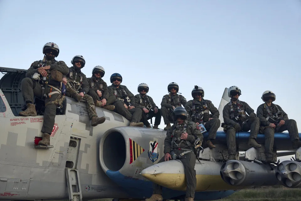 Ukrainian air force pilots sit on an Su-25 ground attack jet as they pose for a photo.