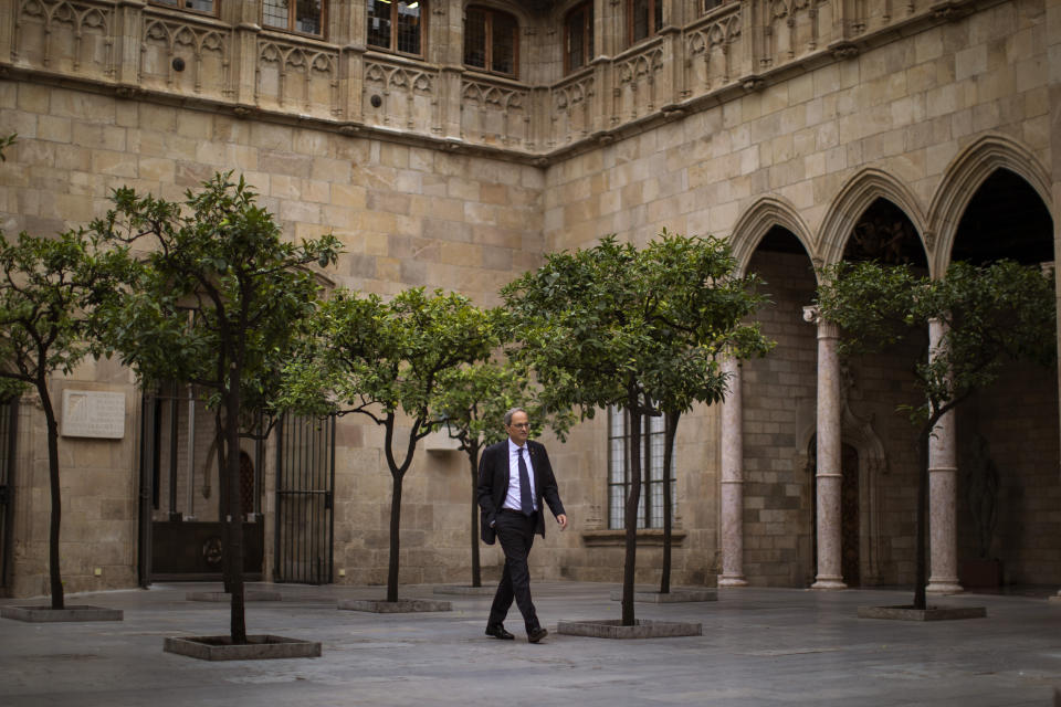 Catalan regional president Quim Torra walks at the Palace of the Generalitat, the headquarters of the Government of Catalonia, ahead of an interview with The Associated Press in Barcelona, Spain, Monday, Oct. 21, 2019. The leader of Catalonia says that the massive protests that have often spiraled into violent clashes with police this week won't cease until the Spanish government accepts to listen to separatists' demands. (AP Photo/Emilio Morenatti)