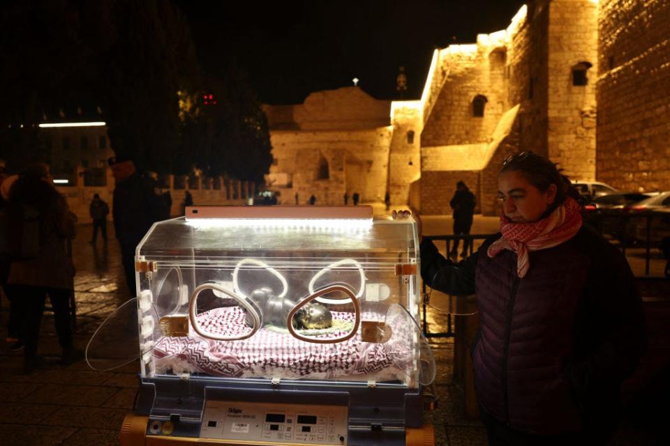 Palestinian artist Rana Bishara stands next to her installation of baby Jesus in an incubator at the entrance to the Church of the Nativity
