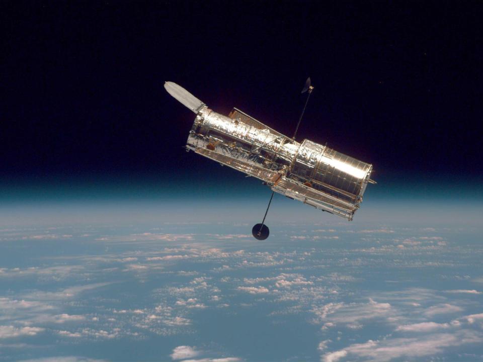 hubble telescope in space above earth clouds