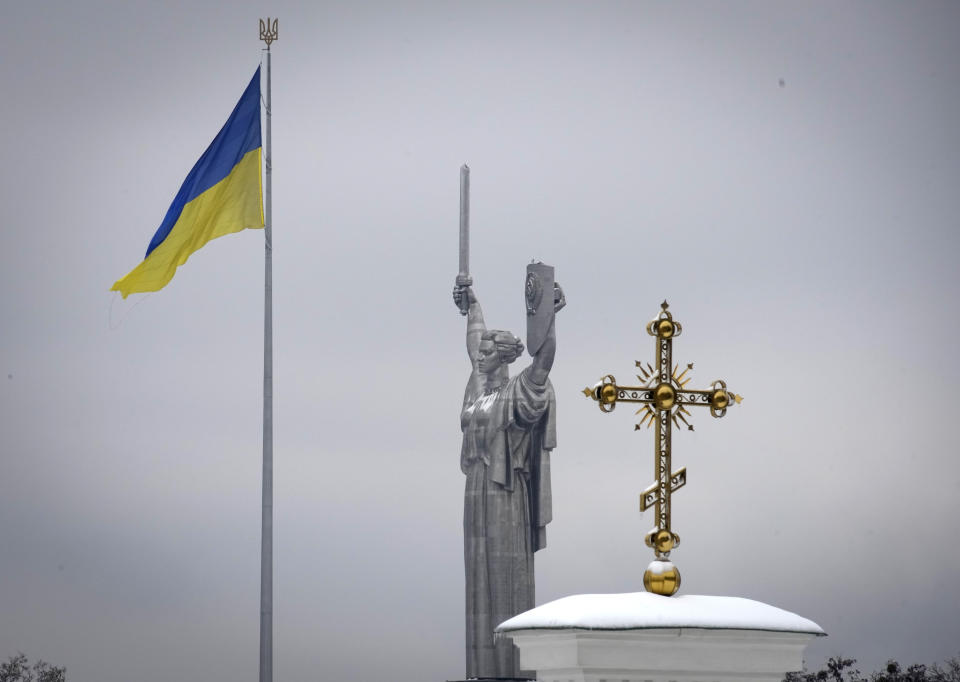A cross of the Pechersk Lavra monastic complex is seen against background of the Ukrainian national flag and the Motherland Monument in Kyiv, Ukraine, Tuesday, Nov. 22, 2022. Ukraine's counter-intelligence service, police officers and the country's National Guard searched one of the most famous Orthodox Christian sites in the capital, Kyiv, after a priest spoke favorably about Russia – Ukraine's invader – during a service. (AP Photo/Efrem Lukatsky)