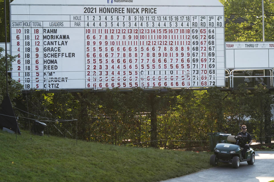 A police officer sits on a cart under the scoreboard following the third round of the Memorial golf tournament Saturday, June 5, 2021, in Dublin, Ohio. Jon Rahm was notified he tested positive for the coronavirus, knocking him out of the tournament after finishing his round. (AP Photo/Darron Cummings)
