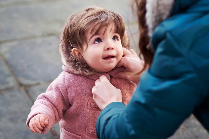 mom buttoning up a toddler's coat