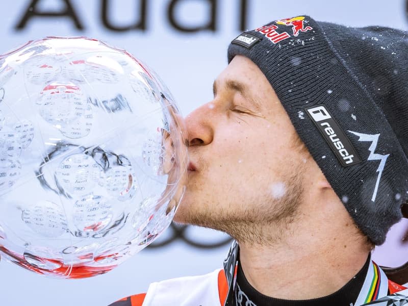 Swiss ski racer Marco Odermatt celebrates with the trophy at the award ceremony of the Men's Overall downhill World Cup. Johann Groder/APA/dpa