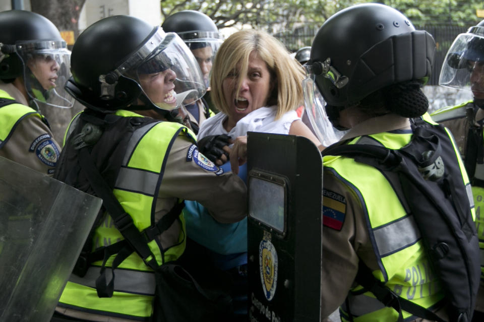 Una mujer es empujada por la Guardia Nacional Bolivariana mientras intenta llegar al edificio del Consejo Nacional Electoral (CNE) durante una protesta en contra del presidente de Venezuela Nicolás Maduro en Caracas este 18 de mayo, 2016. (AP Photo/Ariana Cubillos)