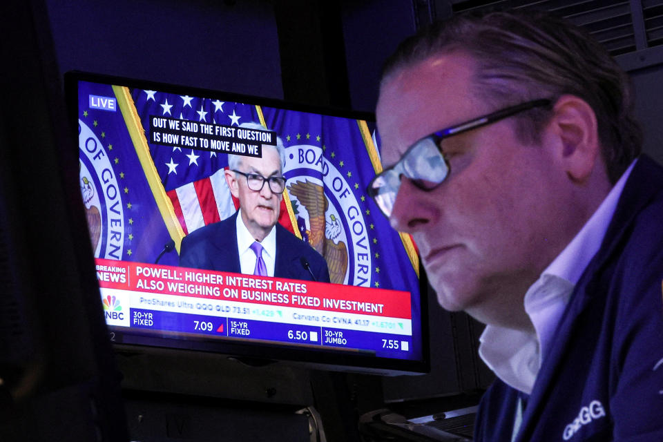 A trader works, as a screen displays a news conference by Federal Reserve Board Chairman Jerome Powell following the Fed rate announcement, on the floor of the New York Stock Exchange (NYSE) in New York City, U.S., December 13, 2023.  REUTERS/Brendan McDermid