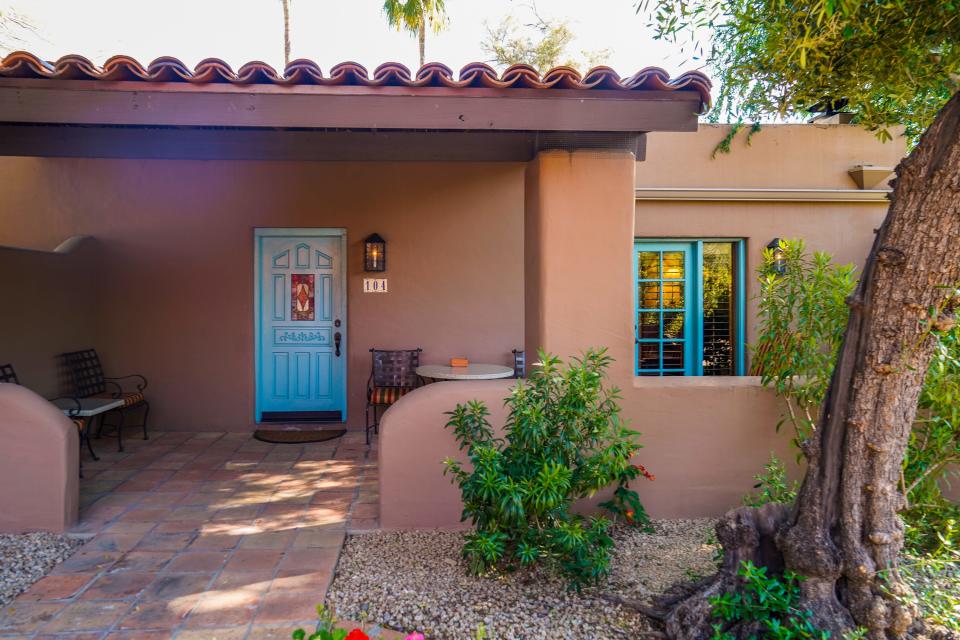 A tan adobe home with a blue door and blue window trimmings