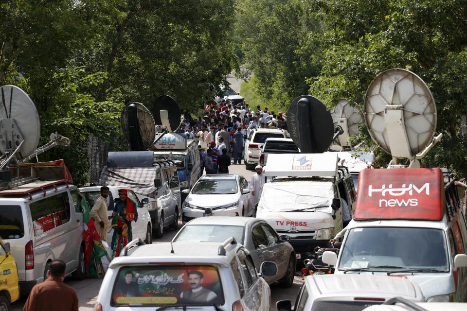 Media vans and supporters of Pakistan's former Prime Minister Imran Khan's party gather outside his residence in Islamabad, Pakistan, Monday, Aug. 22, 2022. Pakistani police have filed terrorism charges against Khan, authorities said Monday, escalating political tensions in the country as the ousted premier holds mass rallies seeking to return to office. (AP Photo/Anjum Naveed)