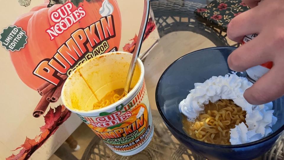 Whipped cream added to a bowl of pumpkin spice Cup Noodle ramen