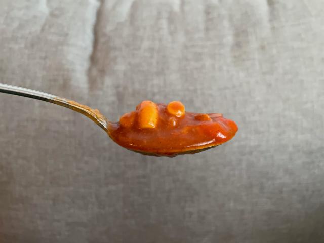 Spoonful of chili mac with gray background