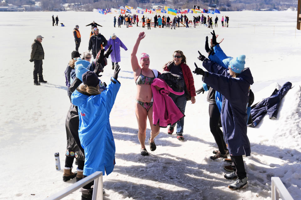 Julie Zeitlinger, of Quebec, Canada, is congratulated by a swim team from Dayton, Ohio, following her performance at the 200 meter freestyle competition in the winter swimming festival on frozen Lake Memphremagog, Friday, Feb. 23, 2024, in Newport, Vermont. (AP Photo/Charles Krupa)
