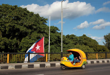 A coco-taxi drives past a Cuban flag at half mast, following the announcement of the death of Cuba's former President Fidel Castro, in Havana, Cuba, November 27, 2016. REUTERS/Stringer