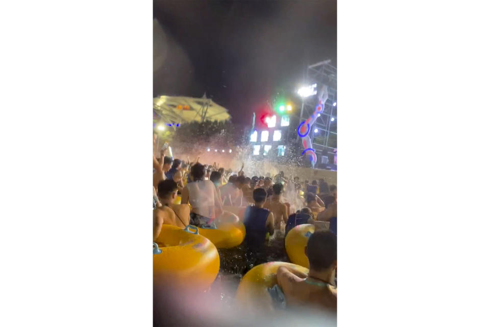 This image made from an Aug 3, 2020 video shows crowd gather in a pool as they watch performers on a stage at Wuhan Maya Beach Water Park in Wuhan, central China. For more than two months, the 11 million residents of Wuhan endured a strict lockdown as coronavirus raced around the city. Now, some are letting loose en masse at rocking nighttime pool parties at the popular amusement park chain. The park reopened in late June, and the crowds have picked up in August. (anonymous photo via AP)