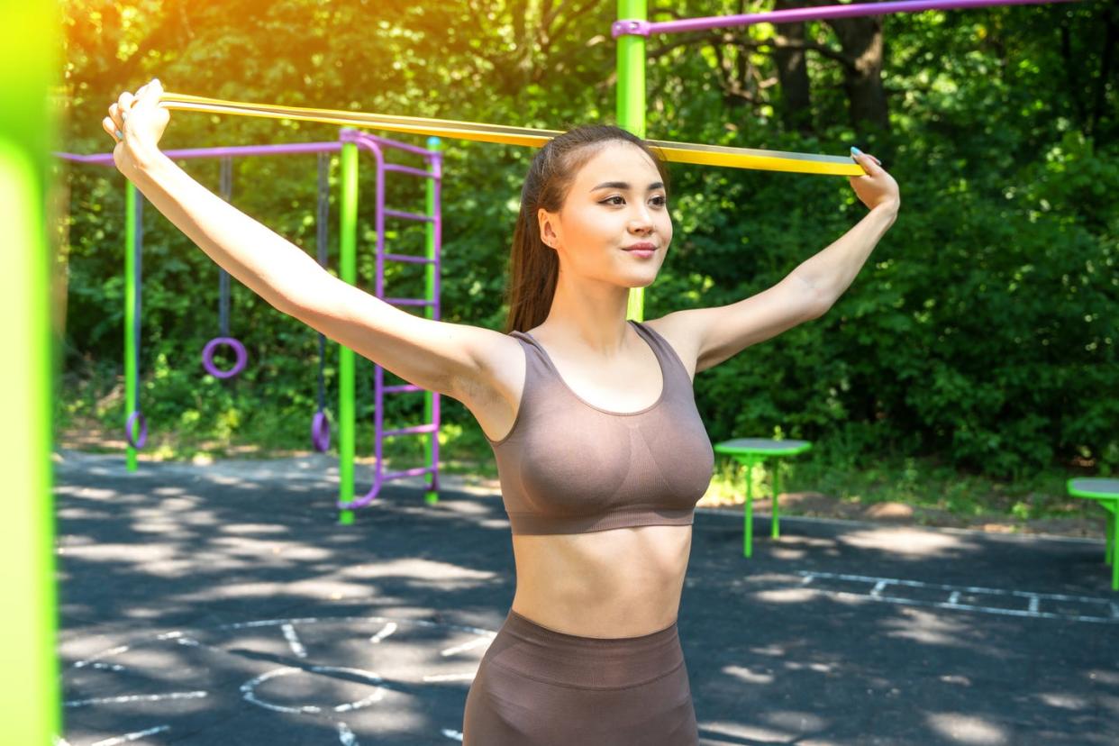 young asian woman training with resistance band at the street sports ground