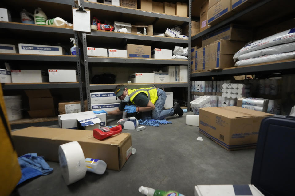 Los Angeles Food Bank custodian Maria Recinos practices "drop, cover, and hold on" at a ShakeOut earthquake drill at the Los Angeles Regional Food Bank in Los Angeles Thursday, Oct. 19, 2023. Up and down the West Coast, the ShakeOut drill was scheduled to begin at 10:19 a.m. PDT with a cellphone-rattling test alert from the region's ShakeAlert earthquake warning system.(AP Photo/Damian Dovarganes)