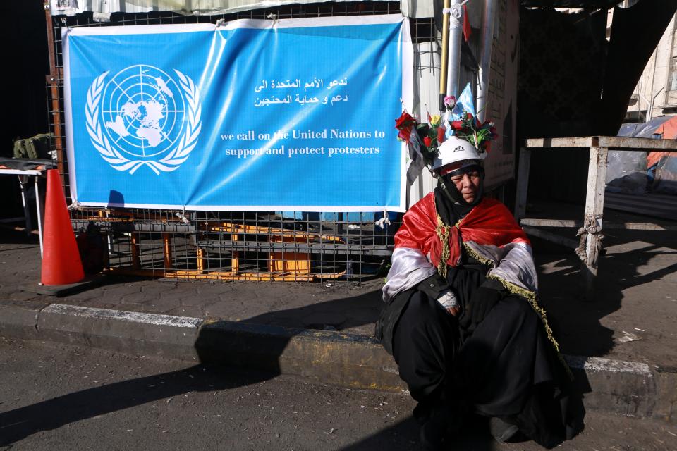 An anti-government protester sits near the United Nations flag on a tent in Tahrir Square during ongoing anti-government protests in Baghdad, Iraq, Saturday, Feb. 1, 2020. (AP Photo/Khalid Mohammed)