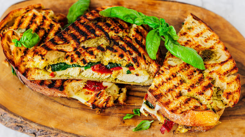 three chicken panini sandwiches on a cutting board