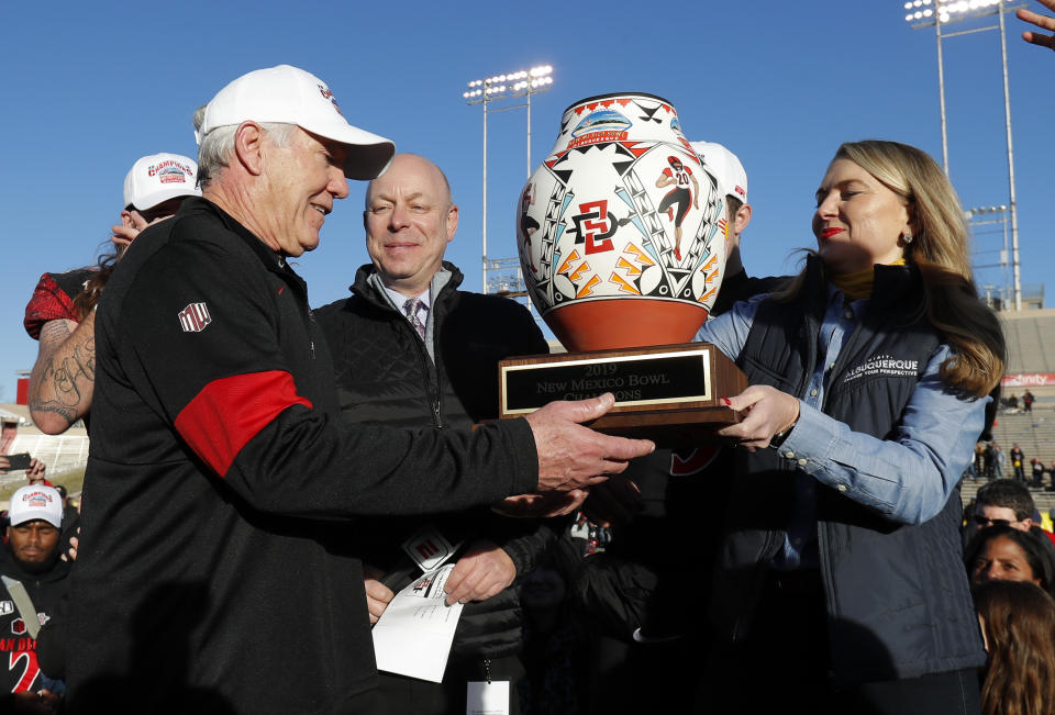 San Diego State coach Rocky Long, left, receives the trophy after his team beat Central Michigan in the New Mexico Bowl NCAA college football game on Saturday, Dec. 21, 2019 in Albuquerque, N.M. (AP Photo/Andres Leighton)