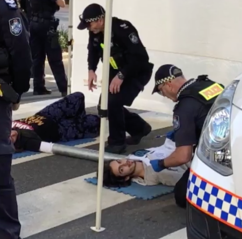 Male and female Adani protestor pictured being dealt with by police.  