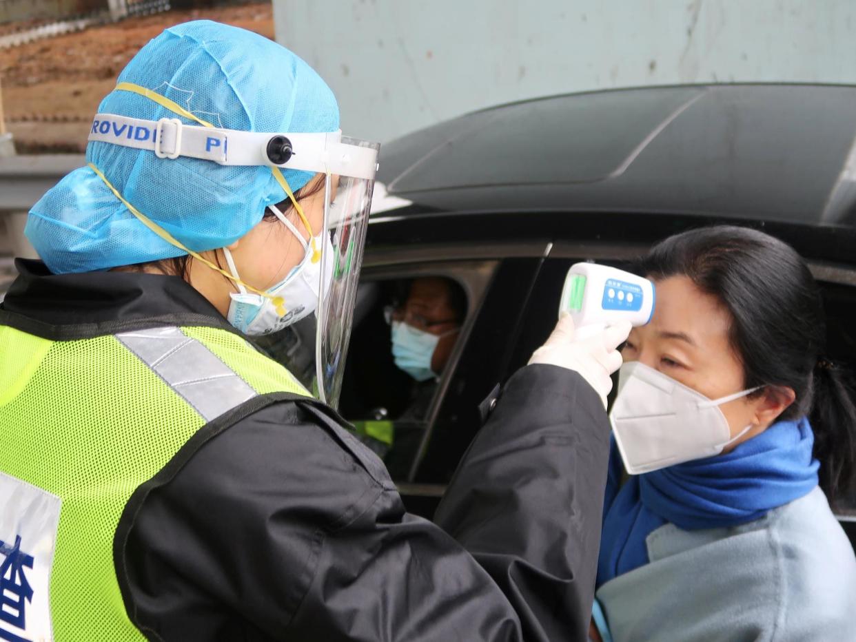 A security officer checks the temperature of a passenger at a motorway toll station: REUTERS