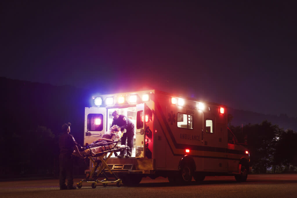 Paramedics carrying patient in ambulance at night (Getty Images)