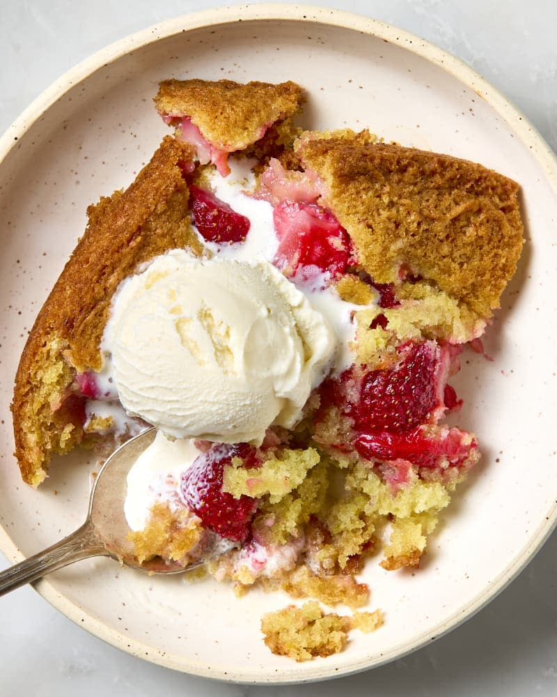 overhead shot of the strawberry spoon cake o a light pink speckled plate, with a scoop of vanilla ice cream on top