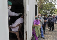 FILE - In this May 6, 2021, file photo, a health worker takes a nasal swab sample of a person to test for COVID-19 as others wait for their turn outside a field hospital in Mumbai, India. The World Health Organization said Monday, May 10, that a worrisome variant was first detected in India may spread more easily. Scientists are still trying to figure out if it resulted in the terrifying surge of infections in the nation, and looking to see if this could this happen elsewhere. (AP Photo/Rajanish Kakade, File)