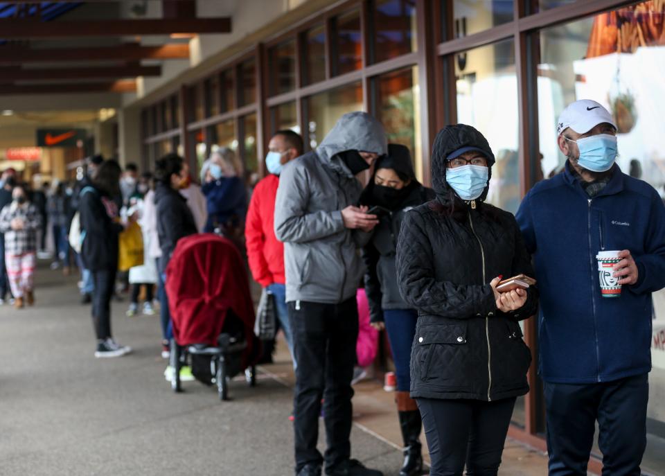Black Friday shoppers wait in long lines at the Nike store on Friday, Nov. 27, 2020 at Woodburn Premium Outlets. Stores were limiting the number of people and taking other precautions to prevent the spread of COVID-19.