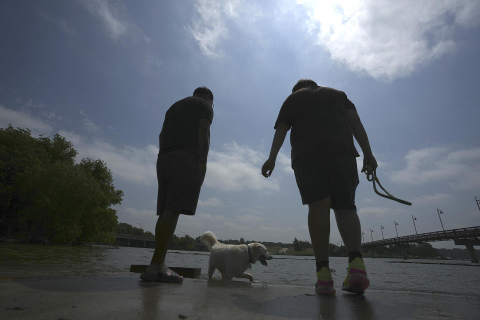 Brothers Fernando, left, and Jacob Ortega watch their dogs at White Rock Lake in Dallas, Tuesday, June 20, 2023. The brothers say they bring their dogs to the lake every day to cool off during summer. (AP Photo/LM Otero)