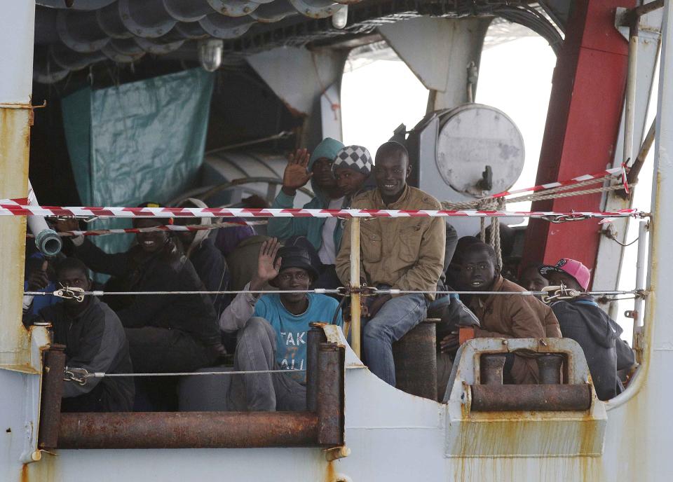 Migrants sit on the Italian Navy patrol ship Spica, as they arrive at the Sicilian harbour of Pozzallo