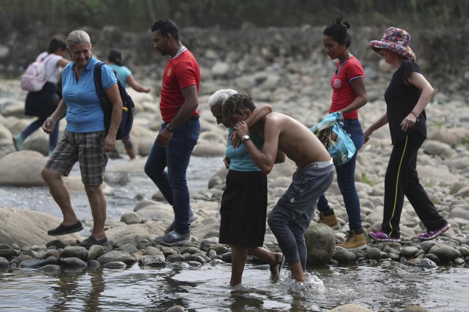 A youth helps an elderly woman walk across the Tachira River into Colombia as people are forced to cross the border illegally due to the closure of the Simon Bolivar International Bridge by Venezuelan authorities, in La Parada, near Cucuta, Colombia, Sunday, March 3, 2019. Last weekend, opposition leader Juan Guaido coordinated a failed effort to bring aid from Colombia and Brazil into Venezuela, where security forces loyal to President Nicolas Maduro blocked the supplies at its border bridges, with Maduro describing Guaido’s gambit as part of a U.S.-backed plot to overthrow him. (AP Photo/Martin Mejia)