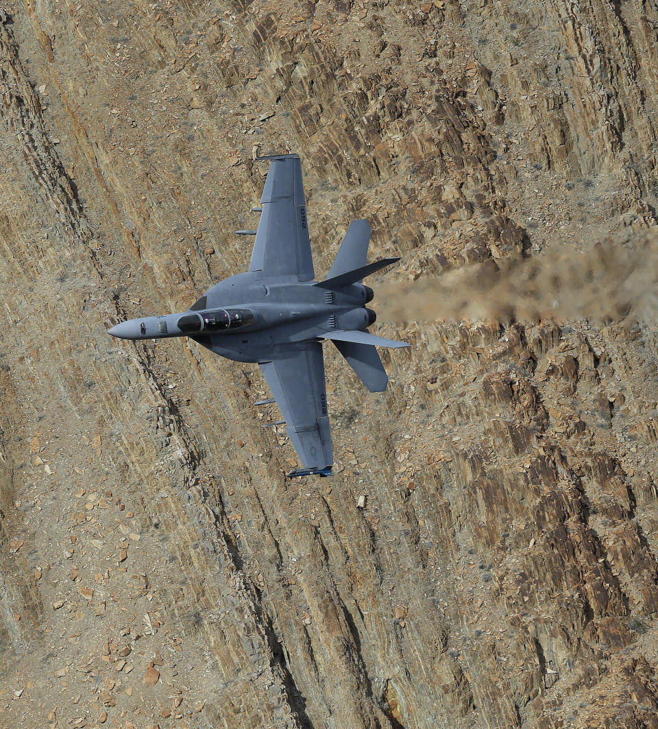 In this Feb. 27, 2017, photo, an F/A-18F Super Hornet from China Lake VX-9 Vampire squadron flies through the nicknamed Star Wars Canyon in Death Valley National Park, Calif. Military jets roaring over national parks have long drawn complaints from hikers and campers. But in California's Death Valley, the low-flying combat aircraft skillfully zipping between the craggy landscape has become a popular attraction in the 3.3 million acre park in the Mojave Desert, 260 miles east of Los Angeles. (AP Photo/Ben Margot)