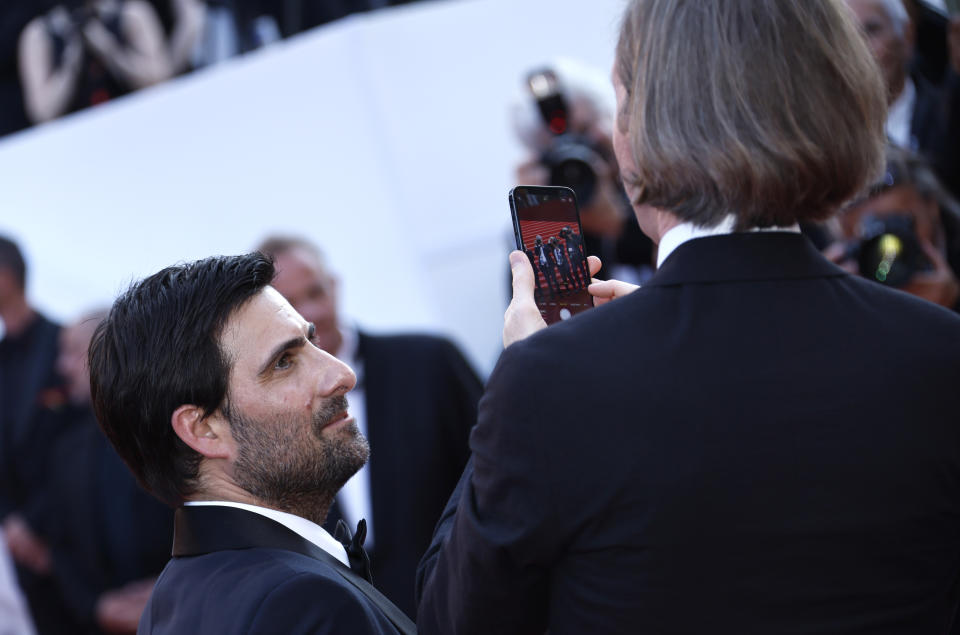 El director Wes Anderson, a la derecha, toma una fotografía a los fotógrafos de la alfombra roja mientras el actor Jason Schwartzman observa, al llegar al estreno de la película 'Asteroid City' en la 76a edición del Festival de Cine de Cannes, en el sur de Francia, el martes 23 de mayo de 2023. (Foto Joel C Ryan/Invision/AP)