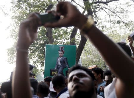 A demonstrator uses his mobile phone to take pictures in front of an poster of United Nations (U.N.) High Commissioner for Human Rights Zeid Ra'ad Al Hussein during a protest against his visit to Sri Lanka, in front of the U.N. head office in Colombo February 6, 2016. REUTERS/Dinuka Liyanawatte