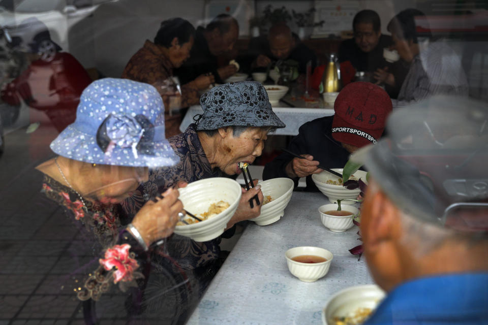 Elderly people have their free vegetarian lunch at Kang's canteen, the Harmonious and Happy Home, one of more than 80 operated by a charity for older people who live alone, in Dingxing, southwest of Beijing Thursday, May 13, 2021. China's leaders are easing limits on how many children each couple can have, hoping to counter the rapid aging of Chinese society.(AP Photo/Andy Wong)