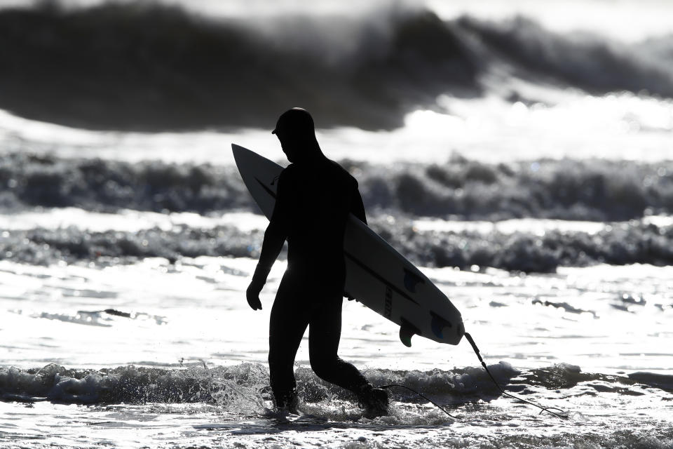 A surfer wades in to defy the lockdown in Tynemouth (Owen Humphreys/PA)