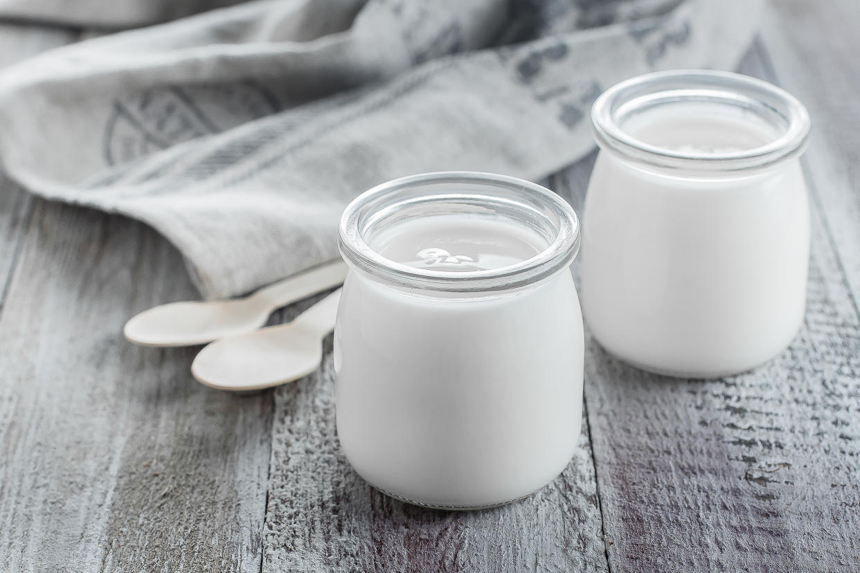 Greek yogurt in a glass jars with wooden spoons on wooden background. Healhty Breakfast Food. Copy space