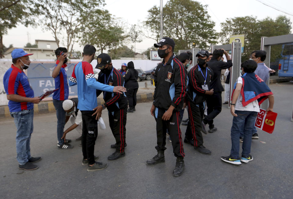 Pakistan police officers frisk cricket fans upon their arrival at the National Stadium to watch Pakistan Super League T20 cricket opening match between Karachi Kings and Quetta Gladiators at National Stadium, in Karachi, Pakistan, Saturday, Feb. 20 2021. Spectators returned to cricket stadiums in Pakistan for the first time since the coronavirus pandemic began when the sixth edition of the Pakistan Super League begins in the southern port city of Karachi. (AP Photo/Fareed Khan)