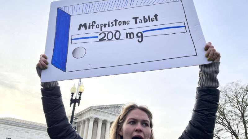 A sign is held at an abortion pill protest