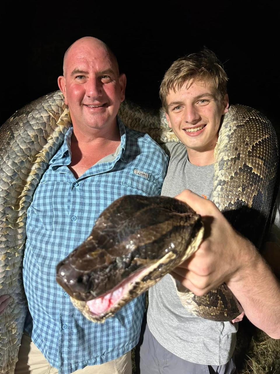 Father and son Mike and Cole pose for a pic with the giant python they just wrangled (Mike Elfenbein/Facebook)